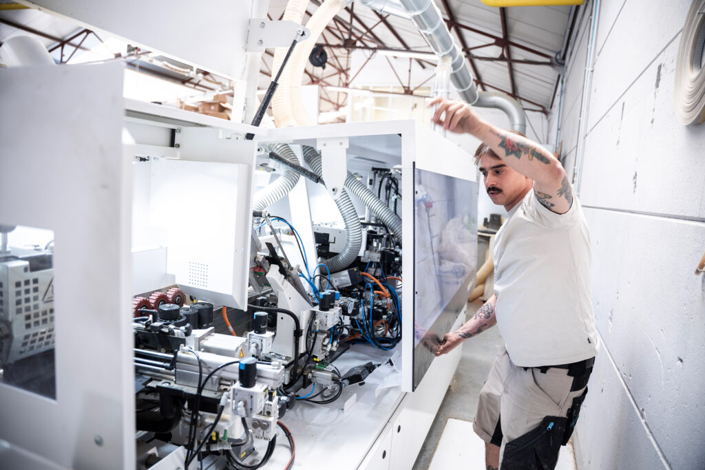 Woodworking craftsman adjusting industrial machinery at La Menuiserie's workshop Copier