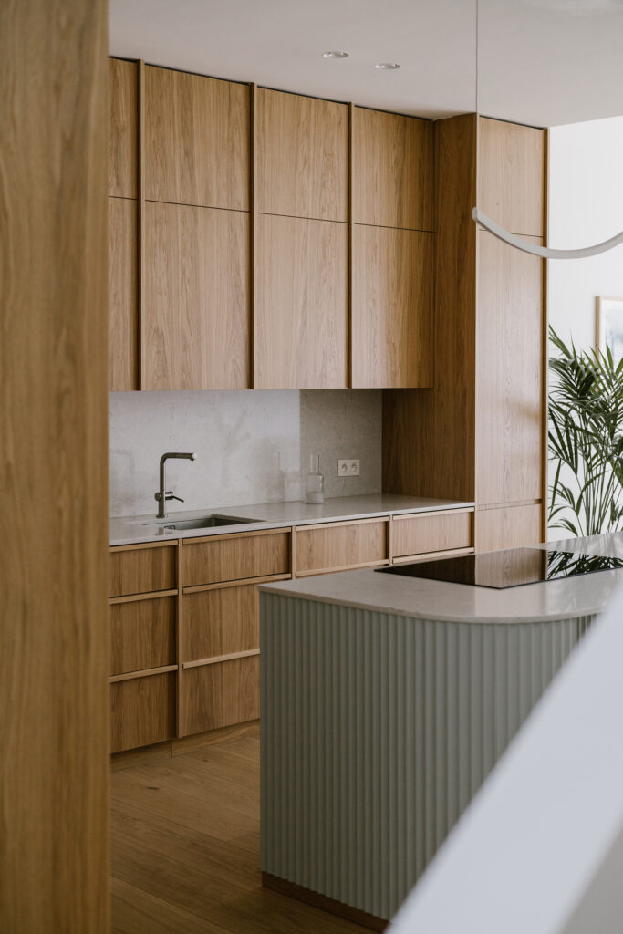 Bespoke oak kitchen with sage green fluted island, stone countertop and integrated cabinetry Copier