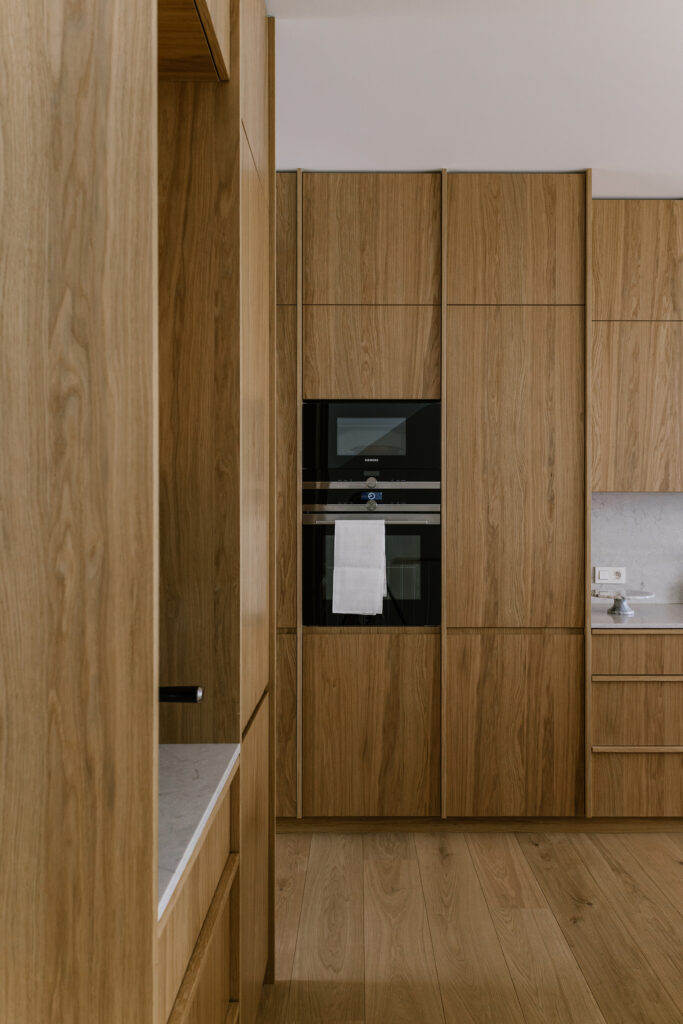 Bespoke oak kitchen with floor-to-ceiling cabinetry, integrated ovens and matching wooden flooring
